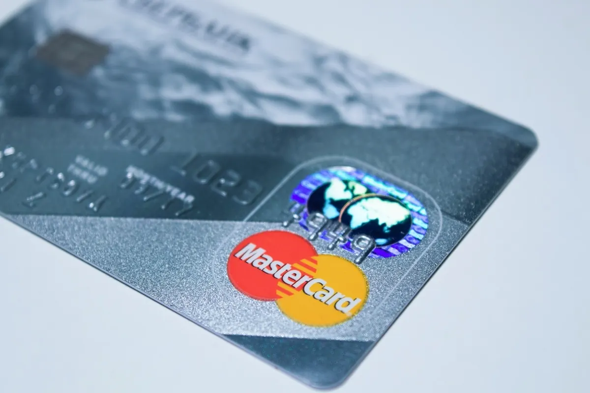 Detaljbild av en Shopify Payments-terminal med ett kreditkort som sveps för en transaktion, vilket symboliserar enkla och effektiva betalningar.